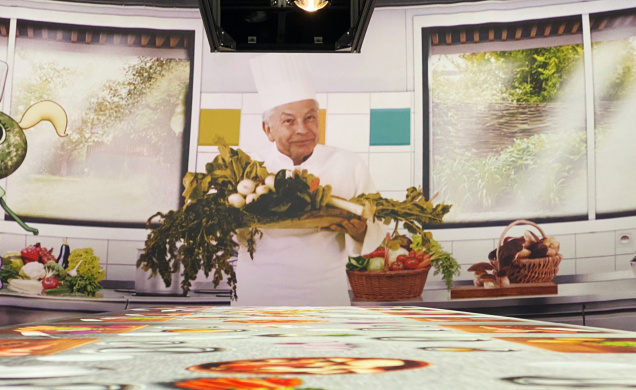 Régis Marcon en scène avec la mascotte Anicia dans une projection immersive